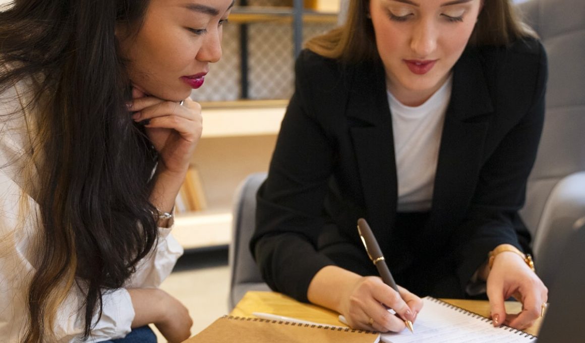 Deux femmes travaillant ensemble avec ordinateur et cahiers.