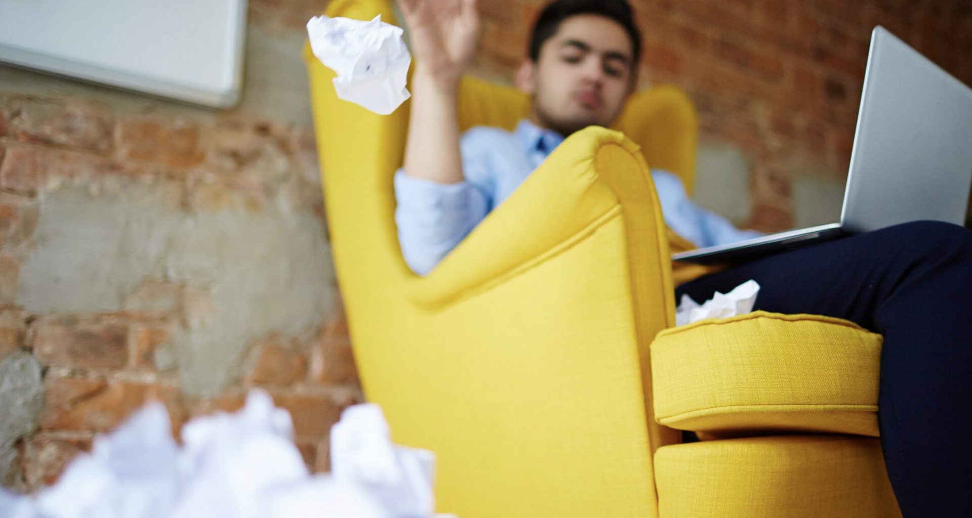 Homme jetant papier dans poubelle près du fauteuil.