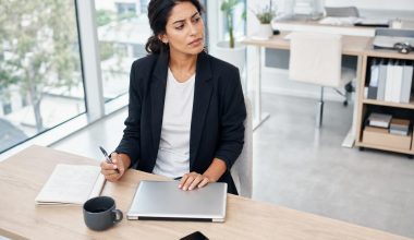 Femme réfléchissant à son bureau avec ordinateur portable