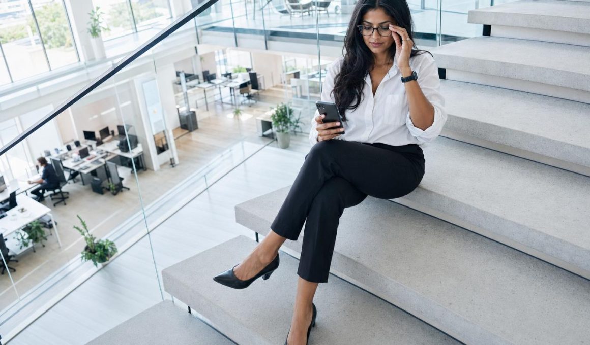 Femme professionnelle assise sur escaliers regardant smartphone