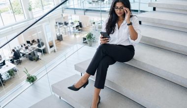 Femme professionnelle assise sur escaliers regardant smartphone
