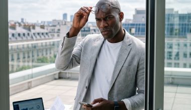 Homme en blazer sur balcon, smartphone en main